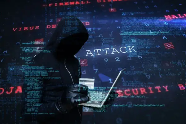 Cyberprzestępca w kapturze planuje ataki hakerskie, używając laptopa i karty kredytowej. W tle widać kod i napisy "VIRUS", "ATTACK", "MALWARE", "SECURITY".